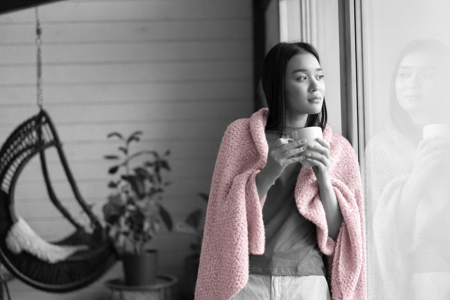 Woman gazing out a window holding a cup of coffee