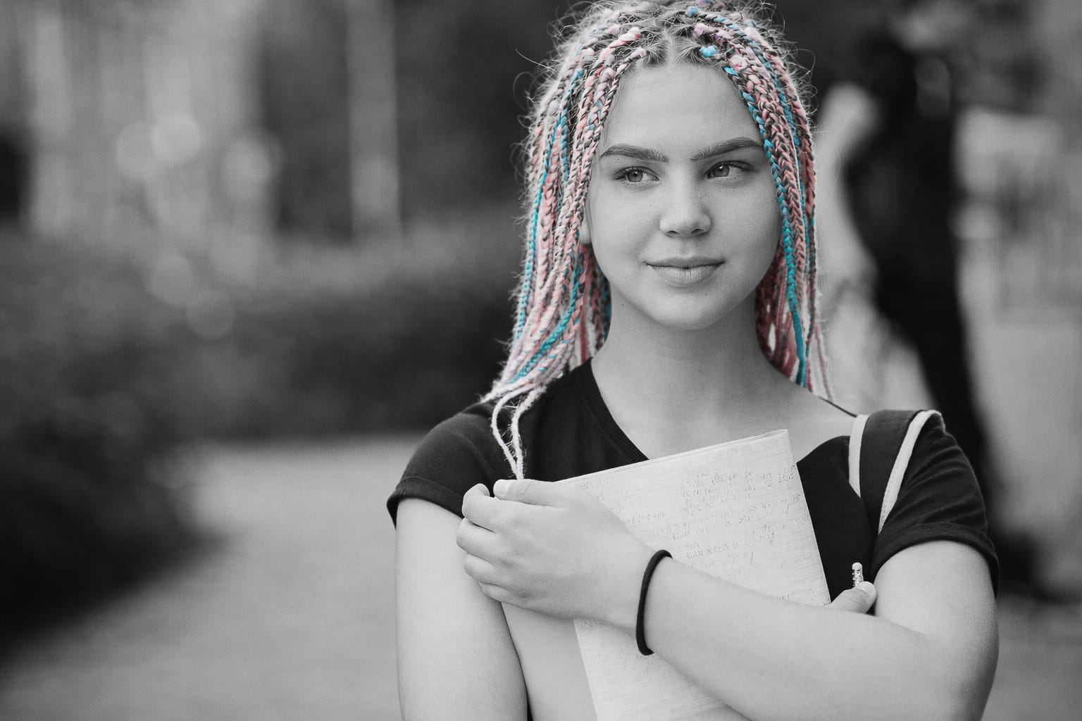 Young woman with colorful braids holding a notebook